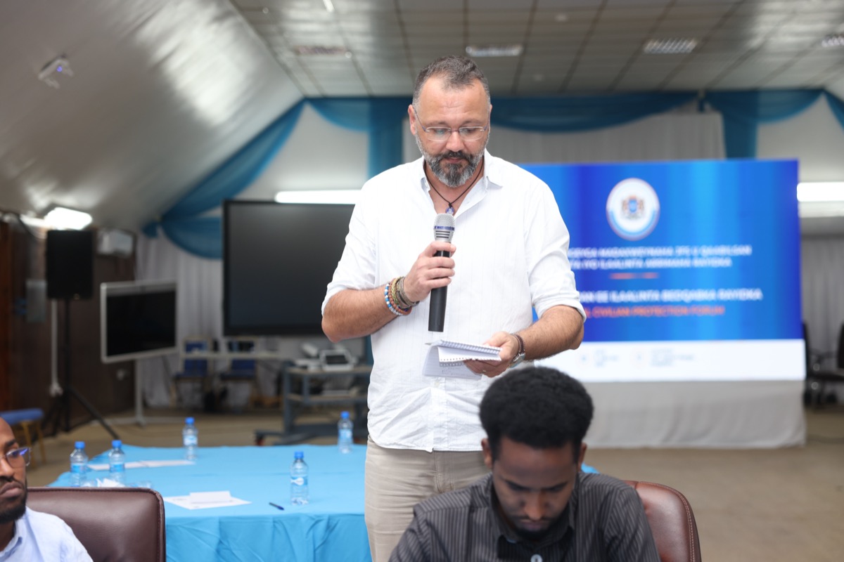 A participant speaking from the floor at the branded backdrop
